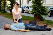 stock photo of pressure  - Woman makes first aid for a man with heart attack in the street - JPG 