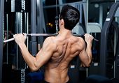 foto of fitness  - Athletic young man works out on training apparatus in fitness gym - JPG 