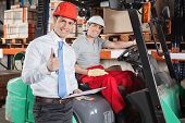 picture of industrial  - Portrait of supervisor gesturing thumbs up with forklift driver sitting behind - JPG 