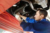 stock photo of industrial  - car mechanic tighten screw in make suspension adjustment with spanner during automobile wheel alignment work at repair service station - JPG 