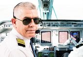 stock photo of transportation  - Airline pilot wearing uniform with epaulettes and headset working in airliner during flight - JPG 