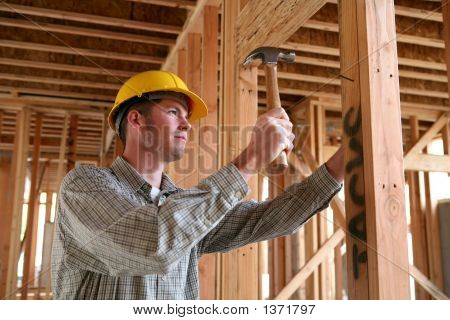 Picture or Photo of A handsome construction man using a hammer to nail together wood