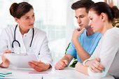 image of medical doctors  - doctor woman offering medical advices to a young couple in office - JPG 