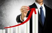 picture of finance  - Businessman drawing a rising arrow on the top of bar graph representing growth - JPG 