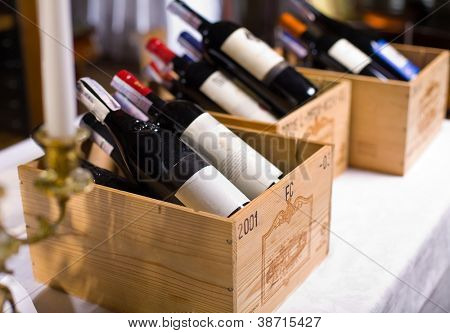 Picture or Photo of Wine bottles in wooden boxes are on the table restaurant.