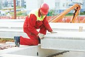 picture of construction  - builder worker in safety protective equipment installing concrete floor slab panel at building construction site - JPG 