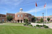 stock photo of buildings  - exterior of a modern American high school building with the American flag on the flag pole and a lush green lawn - JPG 