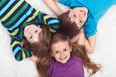 stock photo of group  - Three kids laying on the floor together  - JPG 