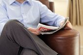 stock photo of newspaper  - Businessman reading a newspaper whilst relaxing on a sofa - JPG 