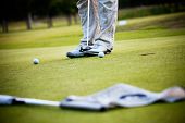 stock photo of golf  - Male golfer putting a golf ball in to hole - JPG 