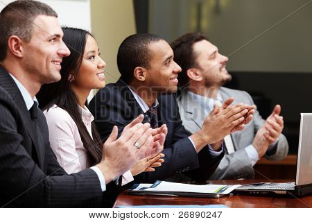 Picture or Photo of Multi ethnic business group greets somebody with clapping and smiling. Focus on woman