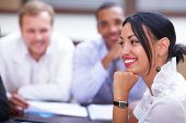 picture of meeting  - Portrait of a beautiful hispanic business woman at a meeting with colleagues in the background - JPG 