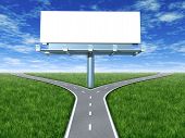 stock photo of dilemma  - Cross roads with billboard in an outdoor display with grass and blue sky showing a fork in the road representing the concept of a strategic dilemma choosing the right direction to go when facing two equal or similar promotional options - JPG 