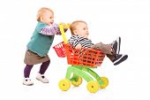 pic of brothers  - Toddler girl pushing her twin brother in a toy cart isolated on white background - JPG 