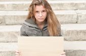 picture of outdoor  - Abandoned teenage girl sitting outdoor on grey stone steps with blank cardboard sign in her hands - JPG 