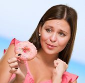picture of worry  - Worried Woman Holding Doughnut against a blue background - JPG 