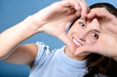 stock photo of holidays  - portrait of attractive happy smiling teen making heart of her hands - JPG 