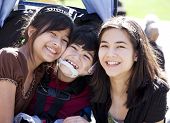 foto of cerebral  - Disabled biracial boy in wheelchair surrounded by his bigger sisters smiling - JPG 