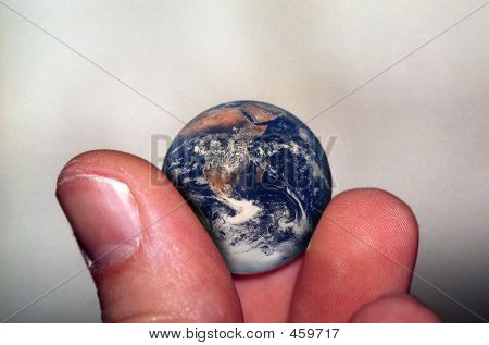 Picture or Photo of Two fingers holding planet earth; earth is marble size. 
** Note: Slight graininess, best at smaller sizes